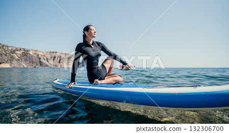 Woman Paddleboard Yoga Ocean - A woman sits in a yoga pose on a paddleboard in the ocean, enjoying a serene moment of relaxation. Woman Paddleboard Yoga Ocean - A woman sits in a yoga pose on a paddleboard in the ocean, enjoying a serene moment of relaxation. 132306700