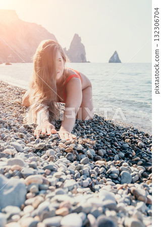 Woman in Red Bikini Kneeling on a Pebble Beach Woman in Red Bikini Kneeling on a Pebble Beach 132306704