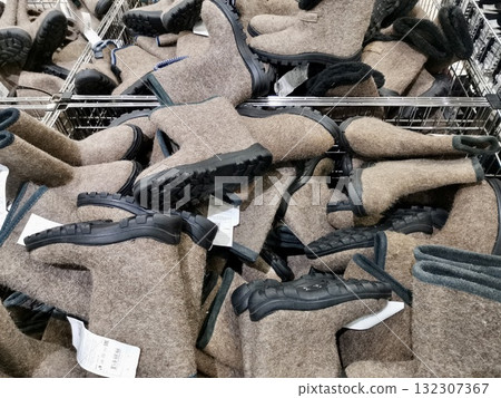 Traditional felt boots on sale in a retail store. Winter footwear displayed in a shopping basket. Traditional felt boots on sale in a retail store. Winter footwear displayed in a shopping basket. 132307367