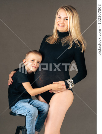 Little boy hugging his pregnant mother with love and warmth. Family portrait showing care and connection. Studio shot Little boy hugging his pregnant mother with love and warmth. Family portrait showing care and connection. Studio shot 132307808