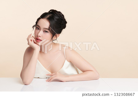 A beautiful young Asian woman with clean, fresh skin against a beige background. Skincare, facial treatment, cosmetology, beauty, and spa. An elegant portrait of an Asian woman. A beautiful young Asian woman with clean, fresh skin against a beige background. Skincare, facial treatment, cosmetology, beauty, and spa. An elegant portrait of an Asian woman. 132308667