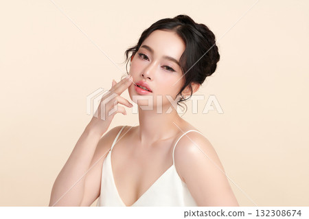 A beautiful young Asian woman with clean, fresh skin against a beige background. Skincare, facial treatment, cosmetology, beauty, and spa. An elegant portrait of an Asian woman. A beautiful young Asian woman with clean, fresh skin against a beige background. Skincare, facial treatment, cosmetology, beauty, and spa. An elegant portrait of an Asian woman. 132308674