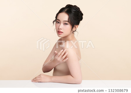 A beautiful young Asian woman with clean, fresh skin against a beige background. Skincare, facial treatment, cosmetology, beauty, and spa. An elegant portrait of an Asian woman. 132308679