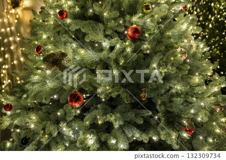 Close-up view of a beautifully decorated Christmas tree with glowing lights and red ornaments, creating a warm and festive holiday atmosphere. Close-up view of a beautifully decorated Christmas tree with glowing lights and red ornaments, creating a warm and festive holiday atmosphere. 132309734