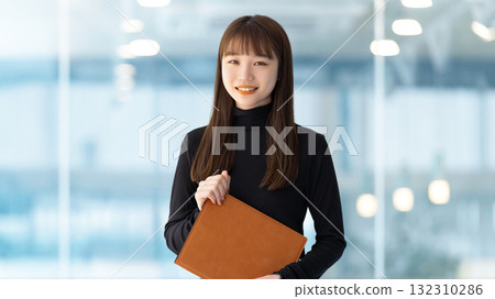 Smiling woman/businesswoman holding a binder 132310286
