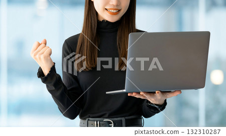 A woman/businesswoman posing in a fist pump while looking at a computer 132310287