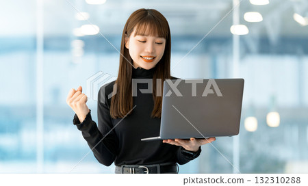 A woman/businesswoman posing in a fist pump while looking at a computer A woman/businesswoman posing in a fist pump while looking at a computer 132310288