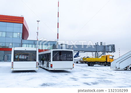 Two airport shuttle buses, a baggage truck and other equipment on the winter airport Two airport shuttle buses, a baggage truck and other equipment on the winter airport 132310299