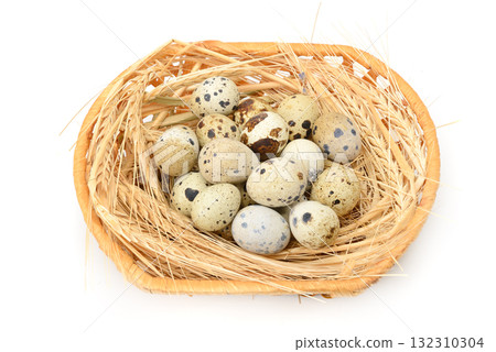 Woven basket filled with straw and speckled quail eggs arranged in rustic natural setting for gourmet and organic food themes Woven basket filled with straw and speckled quail eggs arranged in rustic natural setting for gourmet and organic food themes 132310304