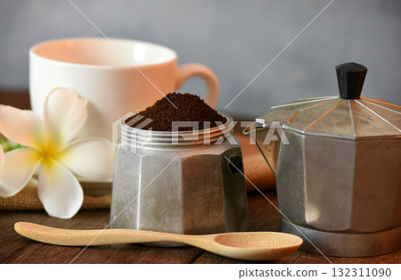 Prepare morning coffee with a Moka pot on a wooden table decorated with flowers. 132311090