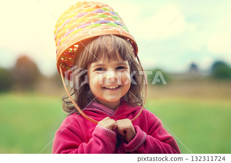 Happy smiling little girl walking through a meadow with a picnic basket on her head Happy smiling little girl walking through a meadow with a picnic basket on her head 132311724