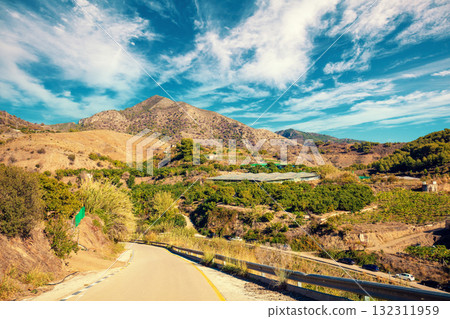 Southern region of Spain. Country road in the mountains. Agriculture greenhouses on the mountain slopes. Descent to Maro beach. Maro, Nerja, Spain 132311959