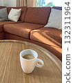 mug of coffee on wooden table in cozy living room with couch 132311964