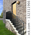 brick house exterior with wooden door, staircase and black metal railing 132311966