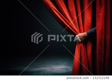 Hand pulling back a red theater curtain to reveal the stage behind for an exciting performance or show 132312246