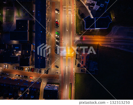 Aerial night view of urban intersection bright streetlights illuminate crosswalks and parked cars, surrounded by buildings, showcasing symmetry, vibrant lighting, and organized infrastructure. Aerial night view of urban intersection bright streetlights illuminate crosswalks and parked cars, surrounded by buildings, showcasing symmetry, vibrant lighting, and organized infrastructure. 132313250