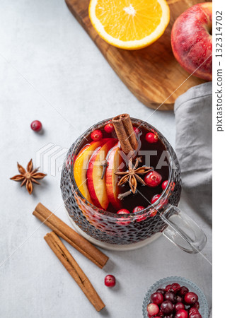 A cup of red mulled wine with spices, orange and apple slices on a light background A cup of red mulled wine with spices, orange and apple slices on a light background 132314702