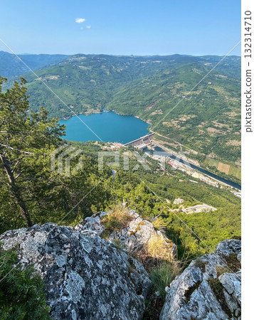 Scenic aerial view of hydroelectric dam on turquoise lake surrounded by lush green forest Scenic aerial view of hydroelectric dam on turquoise lake surrounded by lush green forest 132314710