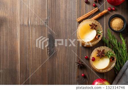 Two glasses of hot apple cider with cinnamon, anise, brown sugar and rosemary on a wooden background 132314746