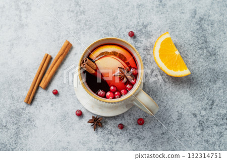 A hot cranberry Christmas drink in a mug on a gray background with cinnamon, berries and fruits. 132314751