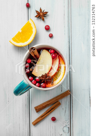 A mulled wine in a mug with cinnamon, berries and fruits on a white wooden background. 132314763