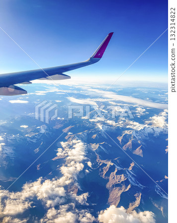 View from Airplane Window Wing and Mountains under Blue Sky View from Airplane Window Wing and Mountains under Blue Sky 132314822