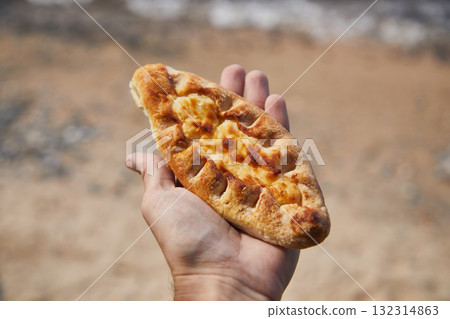Pie with cottage cheese filling in the hand of a man outdoors Pie with cottage cheese filling in the hand of a man outdoors 132314863