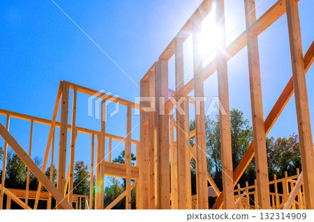 Wooden structure beams takes shape on new home construction activity amidst serene landscape. 132314909