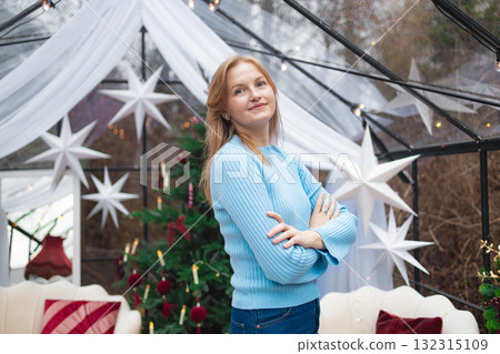 Smiling blonde Caucasian woman standing with crossed arms in festive Christmas interior Smiling blonde Caucasian woman standing with crossed arms in festive Christmas interior 132315109