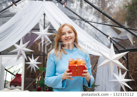 Blonde Caucasian woman opening red Christmas gift box in festive setting Blonde Caucasian woman opening red Christmas gift box in festive setting 132315112