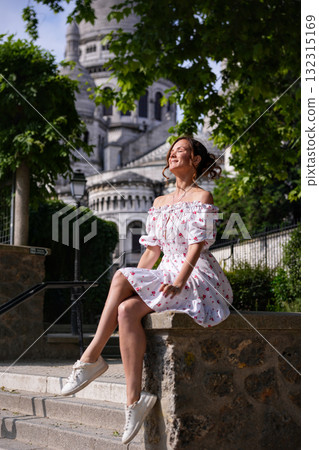 Smiling young woman in summer dress sitting near Sacre Coeur Basilica in Paris Smiling young woman in summer dress sitting near Sacre Coeur Basilica in Paris 132315169