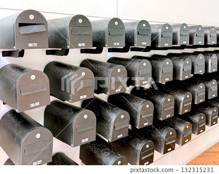 Multiple black mailboxes arranged in rows on a wall in an apartment or office building. Postal delivery concept 132315231