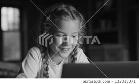 At home, a smiling girl is seated with her computer 132315371