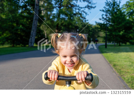 Scooter child. Girl riding scooter toddler. Yellow outdoor activity park road. 132315559