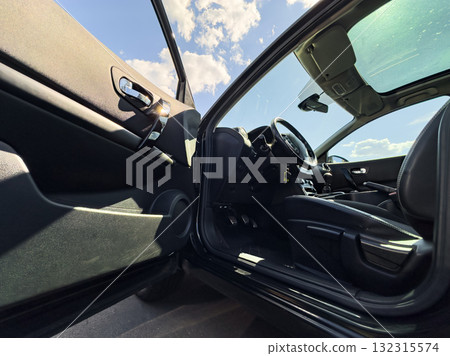 Open car door showing interior in bright daylight with clear blue sky and clouds Open car door showing interior in bright daylight with clear blue sky and clouds 132315574