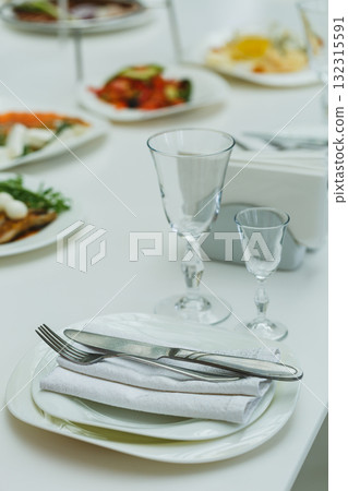 Elegant table setting created for a festive lunch with fine dining plates, glasses, and silverware in a bright, cheerful atmosphere at a cozy restaurant Elegant table setting created for a festive lunch with fine dining plates, glasses, and silverware in a bright, cheerful atmosphere at a cozy restaurant 132315591