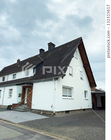 Charming white house nestled in a quiet neighborhood on a cloudy day 132315617