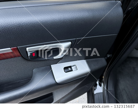 Close view of a car door handle and window control panel in a modern vehicle showcasing sleek design and practicality in everyday use 132315687
