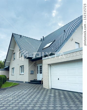 Modern house with patterned driveway and grey sky in suburban area showcases contemporary architecture and design 132315723