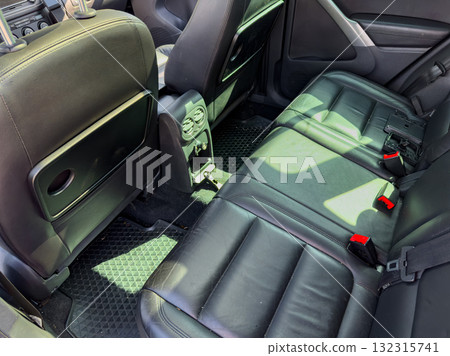 Backseat of a modern vehicle showcasing black leather seats, clean floor mats, and ambient sunlight illuminating the interior during a sunny afternoon drive Backseat of a modern vehicle showcasing black leather seats, clean floor mats, and ambient sunlight illuminating the interior during a sunny afternoon drive 132315741
