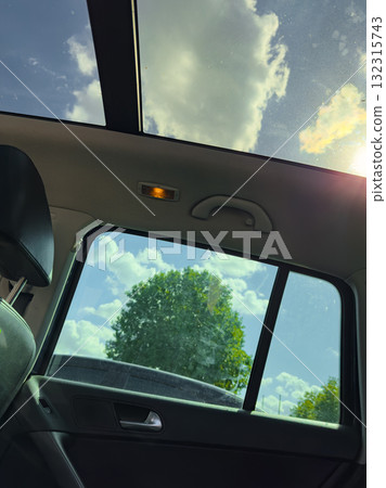 Bright afternoon drive with a view of fluffy clouds and green trees from the car's sunroof Bright afternoon drive with a view of fluffy clouds and green trees from the car's sunroof 132315743
