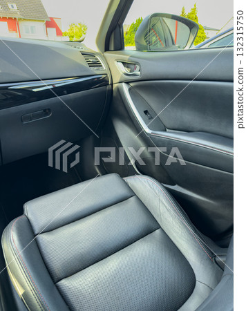 Luxury car interior features sleek black leather seats, a modern dashboard, and a stylish design, inviting comfort and sophistication in a sunny location 132315750