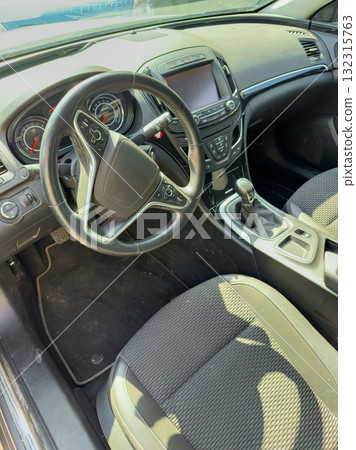 Interior view of a modern sedan showing the steering wheel and gear shift at a sunny location 132315763