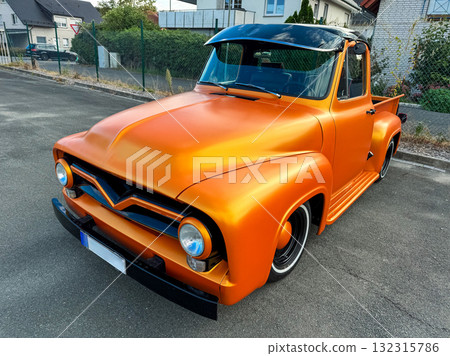 Vintage orange pickup truck shines brightly on a sunny street in the afternoon, showcasing unique design and classic style Vintage orange pickup truck shines brightly on a sunny street in the afternoon, showcasing unique design and classic style 132315786