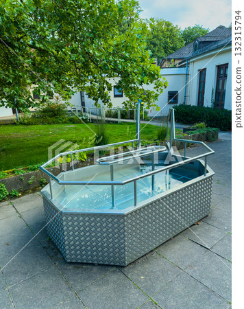 Relaxing outdoor hot tub surrounded by greenery on a sunny day 132315794