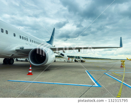 Passengers prepare for departure as a large aircraft stands on the tarmac beneath a dramatic sky filled with clouds Passengers prepare for departure as a large aircraft stands on the tarmac beneath a dramatic sky filled with clouds 132315795