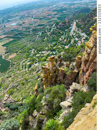 Stunning view of a valley from a rocky cliff with diverse landscape and a distant town during daytime 132315833
