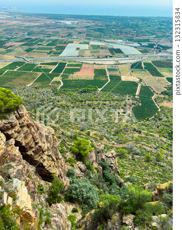 Vast green fields and rocky cliffs merge in a breathtaking landscape overlooking the sea on a clear sunny day near the coastal region 132315834