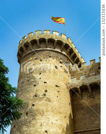 Majestic medieval tower with a waving flag against a clear blue sky in Valencia, showcasing historical architecture and cultural pride Majestic medieval tower with a waving flag against a clear blue sky in Valencia, showcasing historical architecture and cultural pride 132315836
