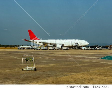 Large passenger airplane parked at airport terminal under clear blue sky during midday Large passenger airplane parked at airport terminal under clear blue sky during midday 132315849